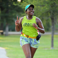 woman smiling and showing peace sign while running